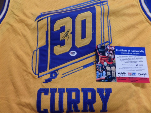 This mint home gold style comes trimmed in team blue, has sewn on everything as well as name on back, and comes black sharpie signed by the future NBA HOF Great. It has a numbered PSA/DNA hologram and COA intact, and value is almost 2 grand on the Golden State Great. AK29221