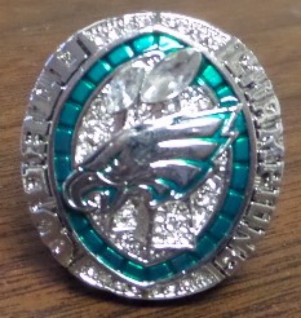 This BRAND NEW Ring was Custom Made to honor the 2024-2025 SUPER BOWL Champion Philadelphia Eagles and their MVP "SAQUON BARKLEY #26". The Ring is Gorgeous with World Champions on the top with and Eagle and the trophies with clear cz stones in shape of football on top and green stones around. One side has the score 40-22 and NFL Logo with SB LIX and 2024, while the other side has "BARKLEY #26" with stones galore. Truly a gorgeous ring to honor the SB Champs.  