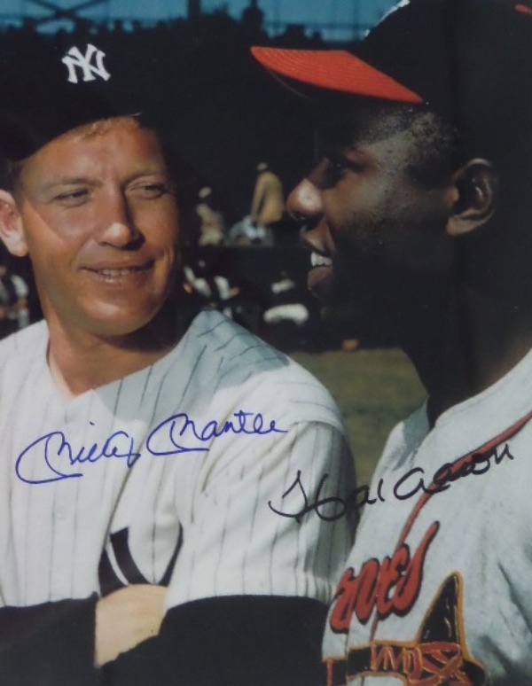 This full color 8x10 photo shows Mickey Mantle and Hank Aaron speaking together before a Yanks/Braves World Series game, and is hand-signed in blue felt tip marker by The Mick, and in black by Hammerin' Hank.  Signatures grade flawless 10's EACH, and the photo is valued well into the mid/high hundreds!
